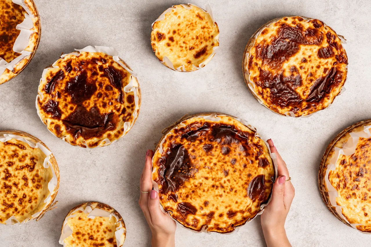 Tartas vascas de Ren&Nata de distintos tamaños sobre una mesa clara, con la superficie tostada y el papel de hornear